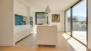 Une cuisine moderne dotée d’un îlot central, de grandes fenêtres et offrant une vue sur l’extérieur.