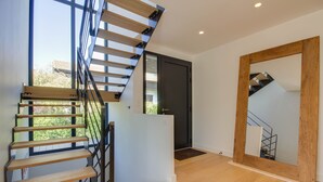 Un escalier moderne avec des marches en bois et des rampes en métal, menant à une porte sombre.