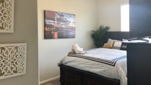 Ein Schlafzimmer mit einem Bett, einem Deckenventilator, einem Gemälde vom Eiffelturm, einer Topfpflanze und einem Fernseher.