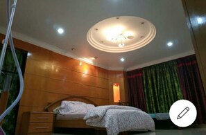 Experience a stylish retreat with a comfortable bed, a wooden panel wall, and a central light fixture.