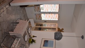 Un coin repas avec une table dressée pour deux personnes, un lustre et un tableau encadré au mur.