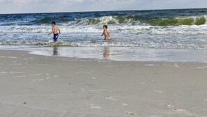 Een strand met twee kinderen die in het water spelen.