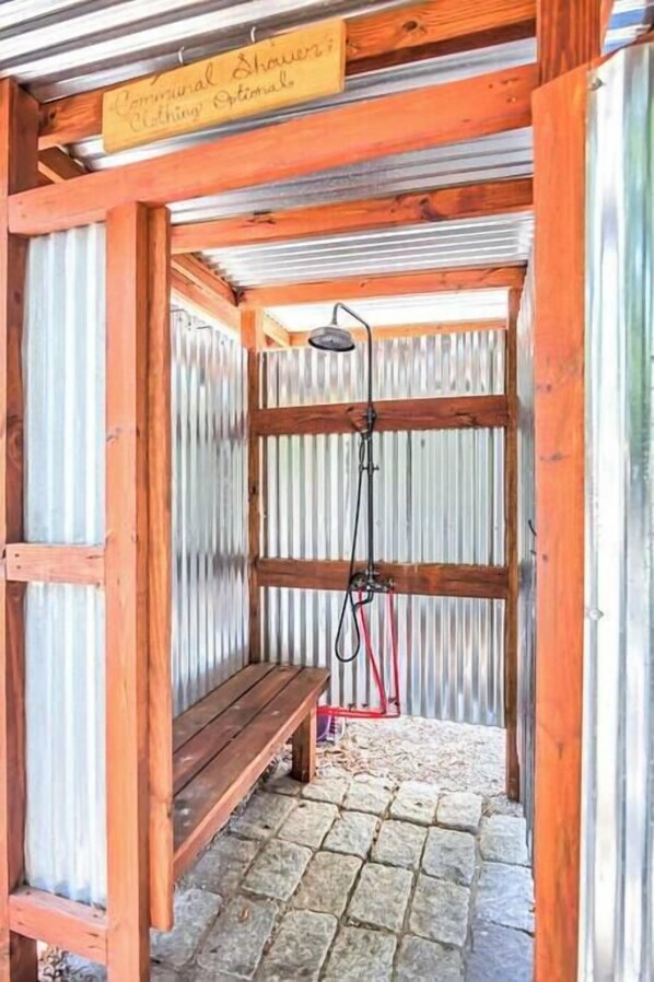 A shower area with a wooden bench and a sign indicating it is a communal shower.