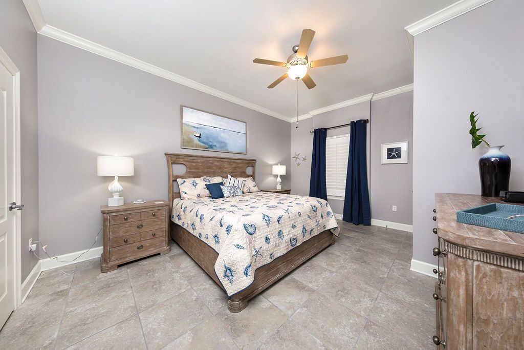 A bedroom with a bed, nightstands, a ceiling fan, and a bathroom with a sink and mirror.