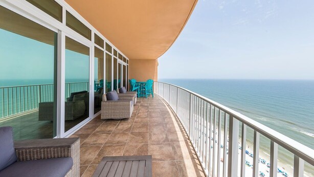 Un balcon avec vue sur l’océan, aménagé avec des meubles en osier et une table.