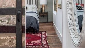 Et soveværelse med seng, et natbord, en lampe og et spejl.