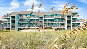 Een meerhoog hotel met balkons en een gazon op de voorgrond.