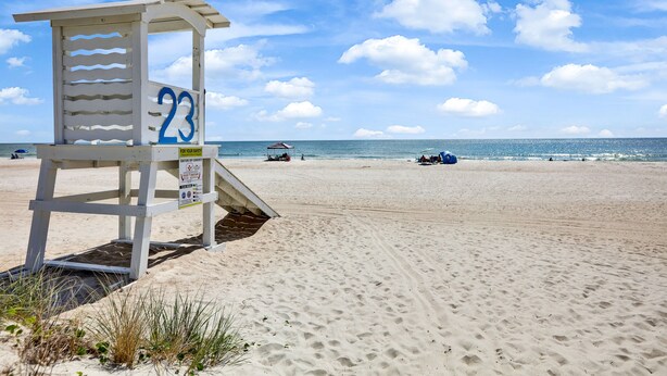 Een redershut met het nummer 23 op een zandstrand, met de oceaan op de achtergrond.