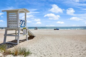 Una torretta di salvataggio con il numero 23 su una spiaggia sabbiosa, con l'oceano sullo sfondo.