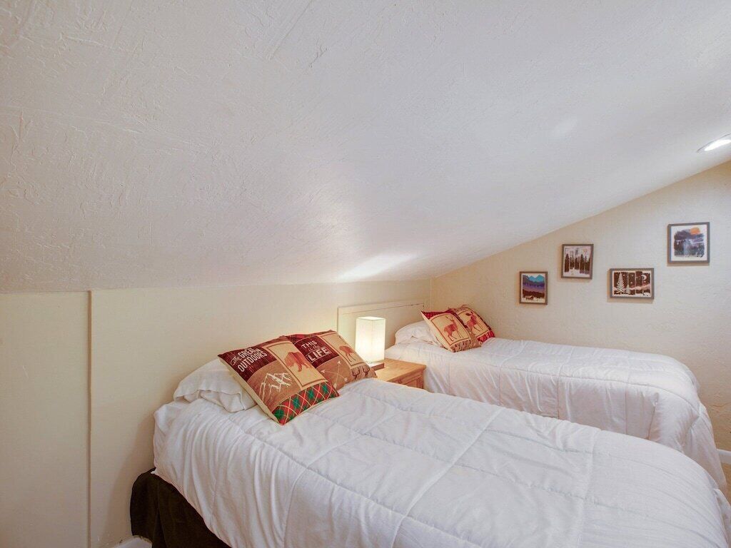 A bedroom with two beds, a nightstand, and a lamp.
