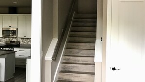 A staircase with a wooden finish, leading to a landing with a white door. - Woodinville Wine Country New Custom Home - Seasonal Pricing - Casa Bambino (Woodinville)