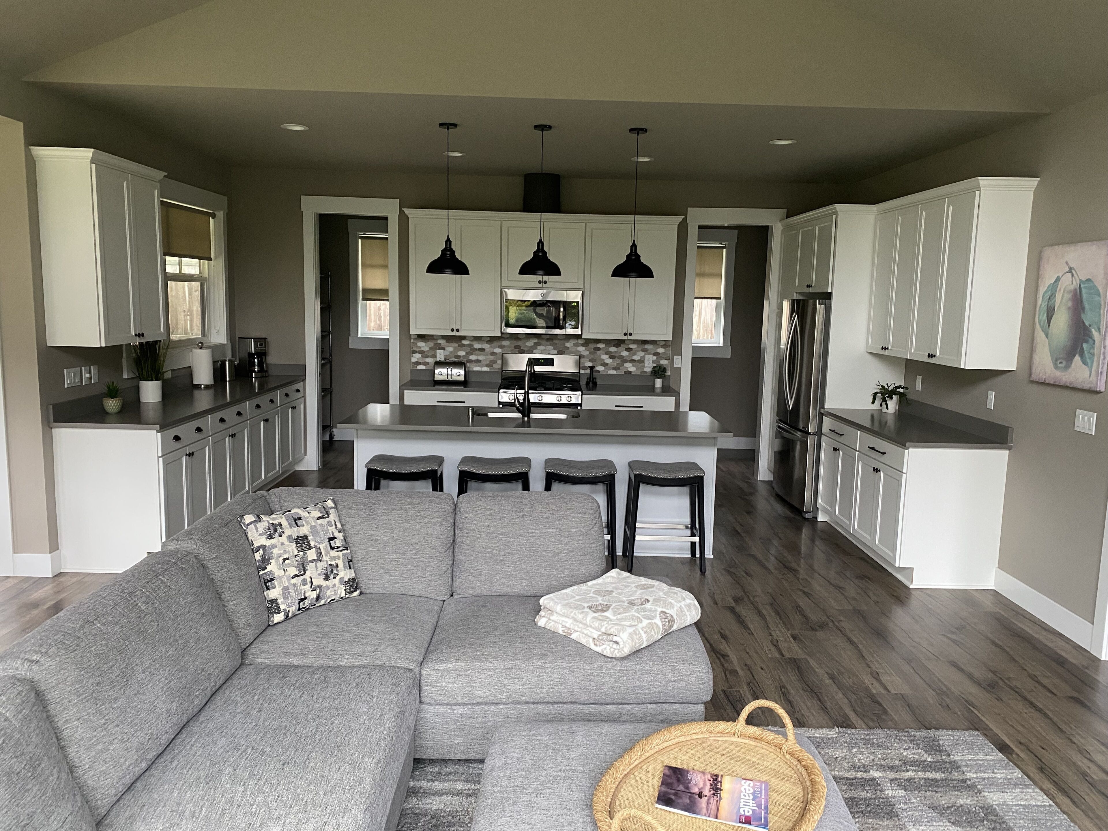 A modern kitchen with white cabinets, a central island with bar stools, and pendant lighting.
