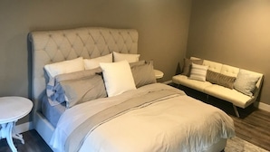 A bedroom with a large bed, a sofa, a small round table, and a ceiling light. - Woodinville Wine Country New Custom Home - Seasonal Pricing - Casa Bambino (Woodinville)