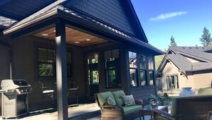 A covered patio area with outdoor furniture, a grill, and a dog. - Woodinville Wine Country New Custom Home - Seasonal Pricing - Casa Bambino (Woodinville)