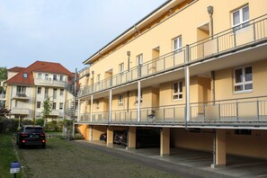 Un immeuble résidentiel à plusieurs étages, doté de balcons et d’un espace de stationnement couvert.