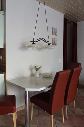 Un espace repas comprenant une table, des chaises, un vase avec des fleurs et des lampes fixées au mur.