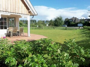 Ett hus med en täckt uteplats, en gräsmatta och ett staket.