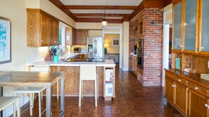 A spacious kitchen with wooden cabinets, a central island, and a brick wall. - Stellamar on Hayden, Close-in Executive Waterfront (Hayden)