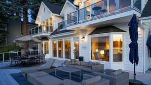 A two-story house with a deck, outdoor furniture, and a large window overlooking a body of water. - Stellamar on Hayden, Close-in Executive Waterfront (Hayden)