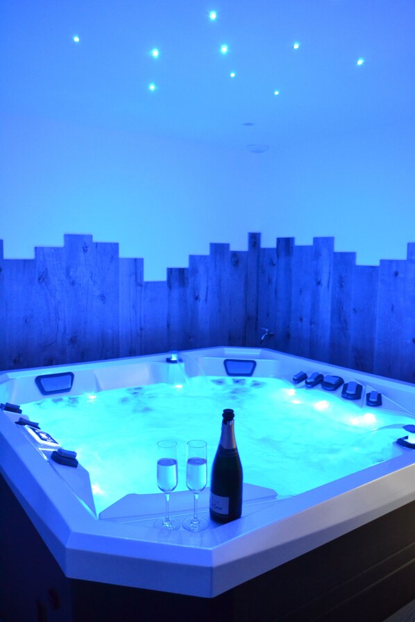 Relax in a hot tub surrounded by a fence, perfect for unwinding with a glass of champagne.