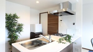 A modern kitchen with a stainless steel sink, a built-in stove, and a wooden cabinet. - Grand Residence Hakataeki Minami (Fukuoka)