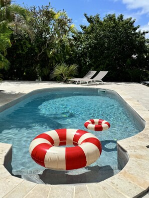 A swimming pool with two lounge chairs and two red and white inflatable rings. - Confortable Villa "Coco" with a private swimming pool (Saint François)