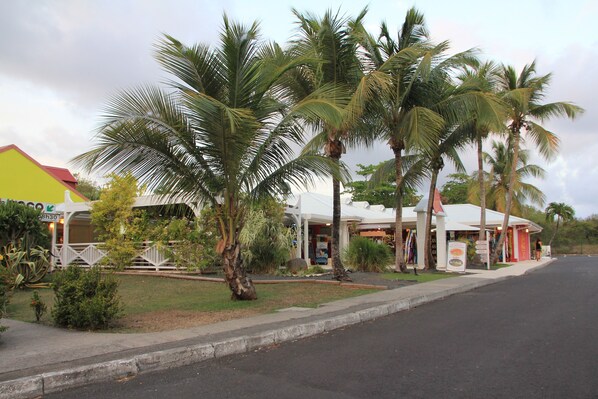 A street with palm trees and a building with a white facade and a red roof. - Confortable Villa "Coco" with a private swimming pool (Saint François)