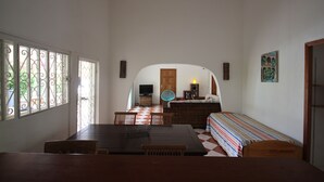 A dining area with a checkered floor, a wooden table, and chairs. There is a sofa with a striped blanket and a television in the background. - Confortable Villa "Coco" with a private swimming pool (Saint François)