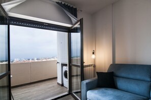 Un balcon donnant sur un paysage urbain, un lave-linge et un canapé bleu.