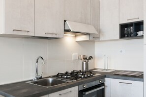 Une cuisine moderne équipée d’une cuisinière à gaz, d’un évier en acier inoxydable et de meubles de couleur claire.