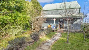 A house with a green roof, a porch, and a stone pathway leading to the entrance. - Stunning Cliff Face and Valley Views (KATOOMBA)