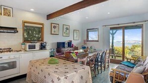 A spacious kitchen with a dining area, large windows, and a view of the outdoors. - Stunning Cliff Face and Valley Views (KATOOMBA)