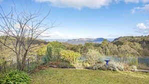 A landscape with a grassy area, trees, and a distant view of hills. - Stunning Cliff Face and Valley Views (KATOOMBA)
