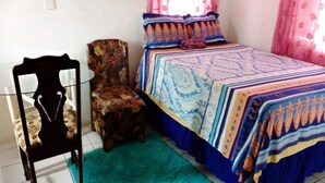 Un dormitori amb un llit, una cadira i una taula petita.