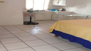 Habitació amb un llit, un ventilador, un rentaplat i armaris.