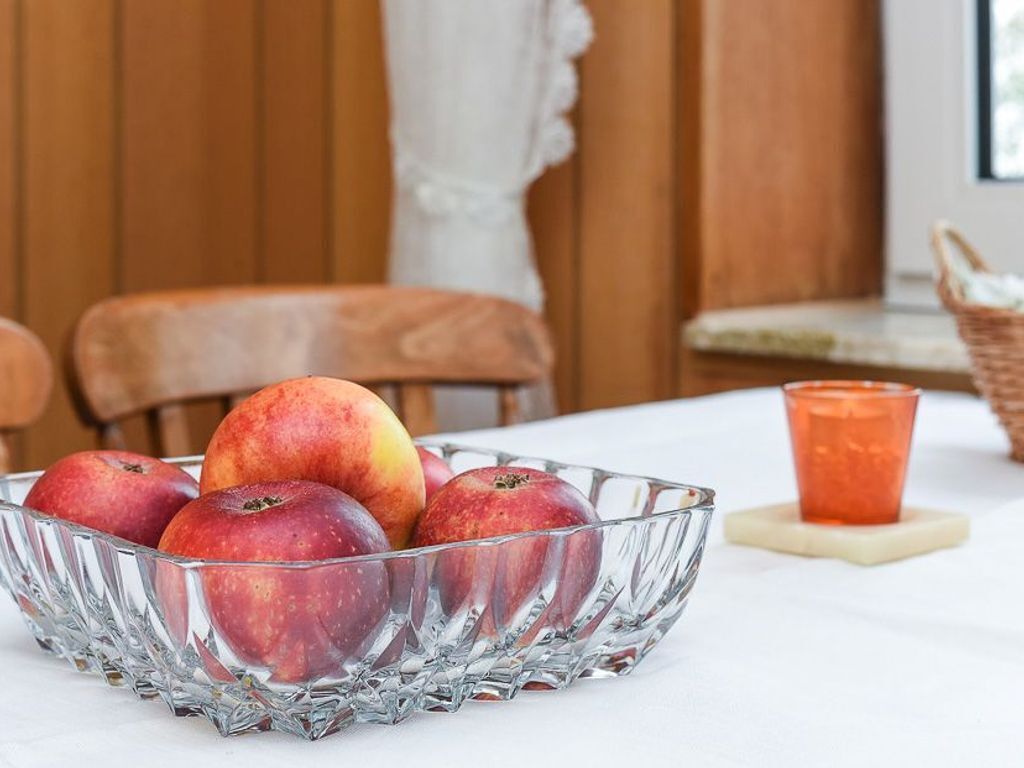 Un saladier en verre transparent contenant des pommes, posé sur une table.