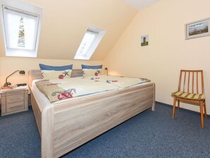 Une chambre à coucher avec un lit, une chaise, une table de chevet et une fenêtre.