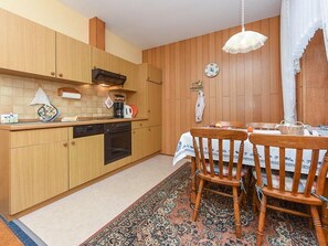 Une cuisine compacte dotée de meubles en bois, d’un lave-vaisselle et d’un coin repas avec une table et des chaises.