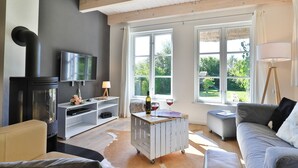 Un salon avec un téléviseur, une cheminée, un canapé et de grandes fenêtres.