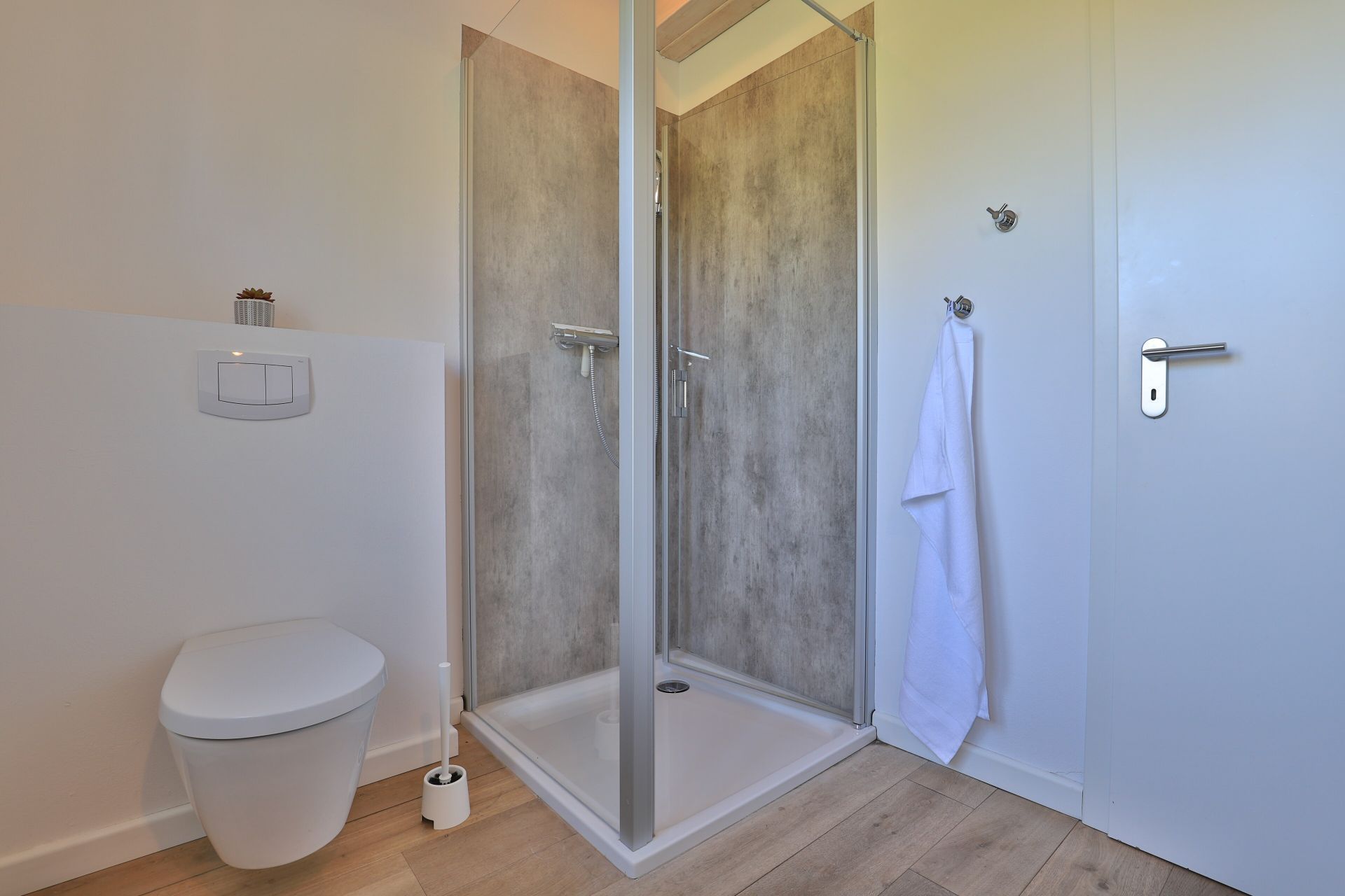 Ein modernes Badezimmer mit einer Duschkabine, einer Toilette und einem Handtuchhalter.