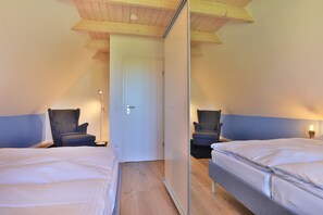 A room with two beds, a door, and two chairs.