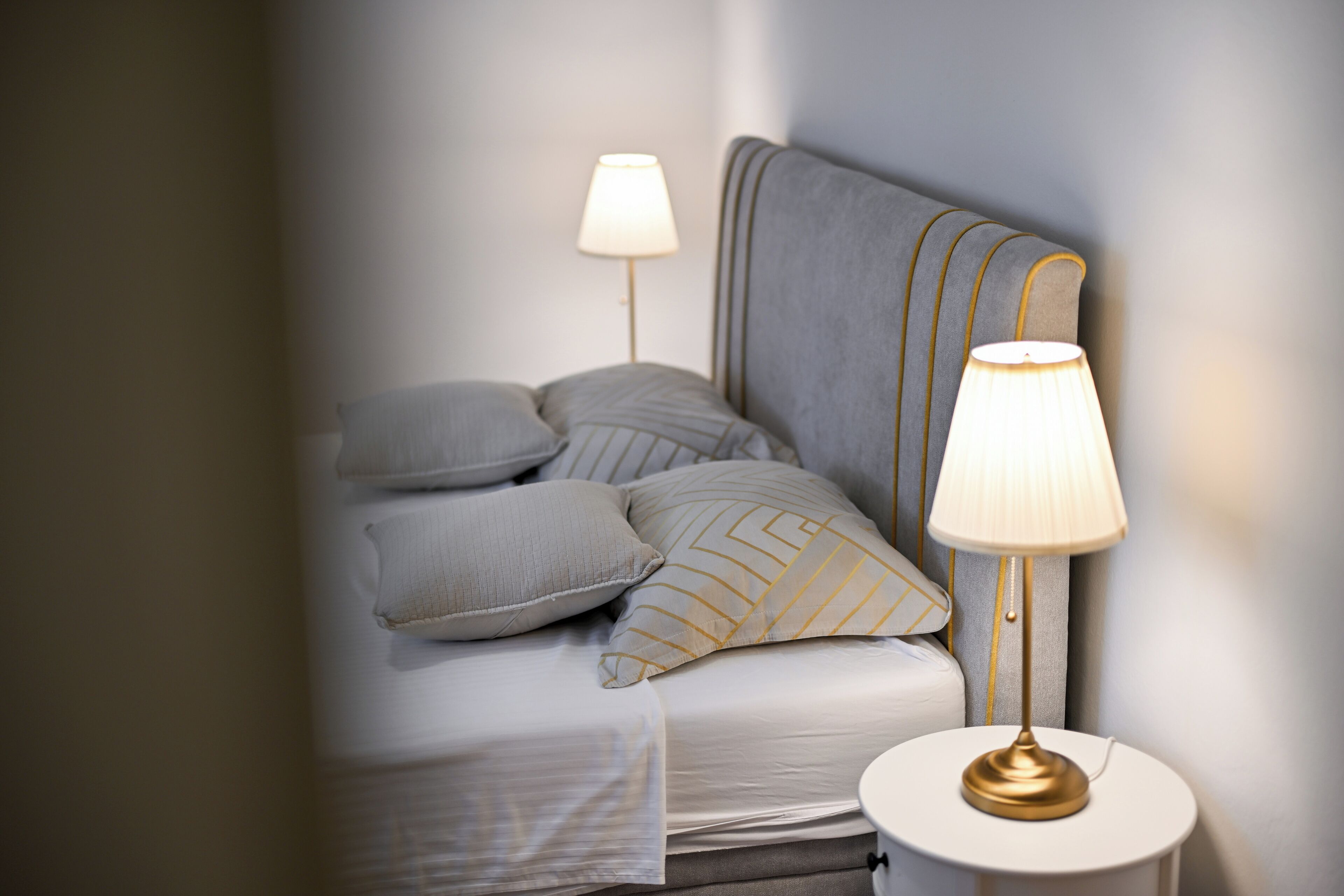 Un lit bien fait, avec des oreillers, une lampe de chevet et une table de nuit.