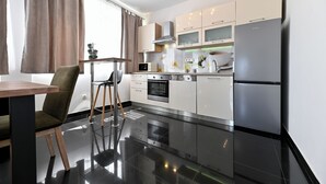 Una cocina moderna con electrodomésticos de acero inoxidable, un comedor con mesa y sillas de madera, y un amplio ventanal con cortinas.