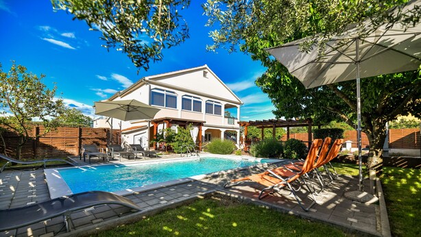 Una casa con piscina, mobiliario exterior y una pérgola.