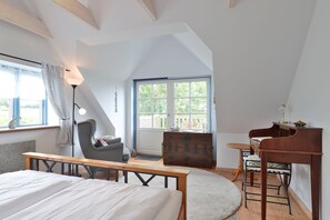 A bedroom with a bed, a desk, a chair, a piano, a window, and a lamp.