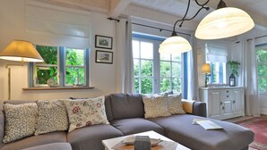 A cozy living room with a sectional sofa, a coffee table, and pendant lighting.
