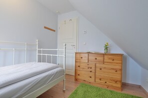 Un dormitorio con una cama, un aparador de madera y una alfombra verde.