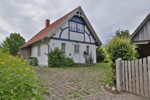 Une maison traditionnelle avec un toit en tuiles, un porche à l’avant et une clôture en bois.