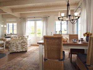 A dining area with wicker chairs, a wooden table, and a chandelier.