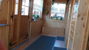 A wooden cabin interior with a bench, potted plants, and a window with lace curtains. - 4-5 people, double room with kitchen u. balcony (Zakopane)